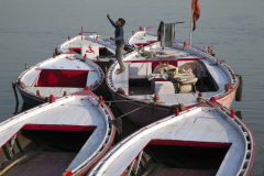A young Indian boy flys a kite off of boats moored on the Ganges River in Varanasi, India.