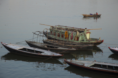 An Indian boy rows his boat past a group of colorful moored boats on the Ganges River in Varanasi, India.